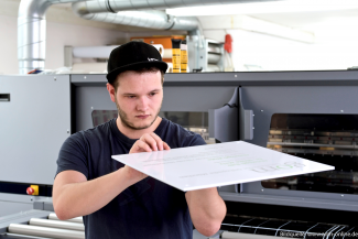 Auszubildender zum Schilder- und Lichtreklamehersteller prüft Druck.